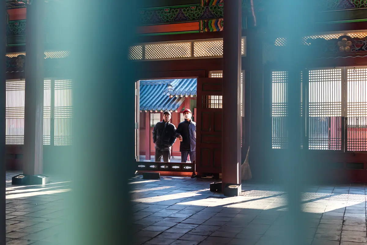 Two middle-aged Korean men look into a traditional Korean building at Deoksugung Palace in Seoul