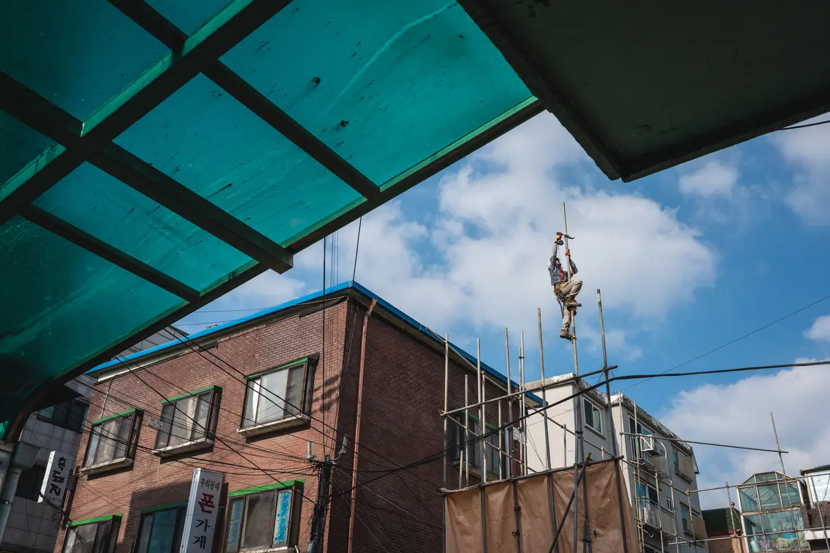 Korean construction worker climbs scaffolding and works with tools in Mangwon-dong, Seoul