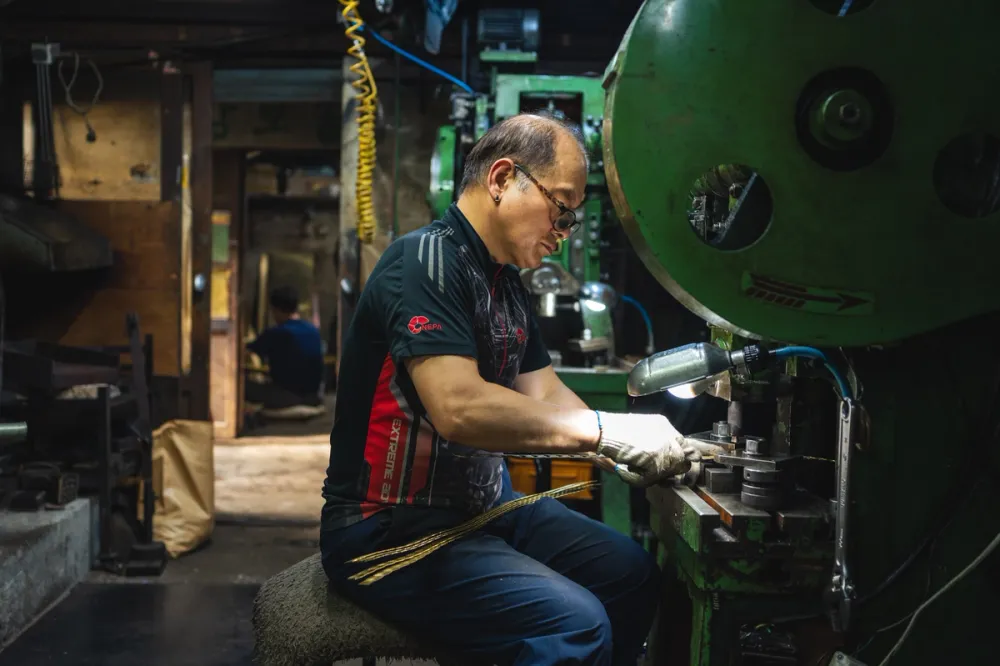 A worker operating industrial machinery in an industrial workshop in Seoul, focused on his work.