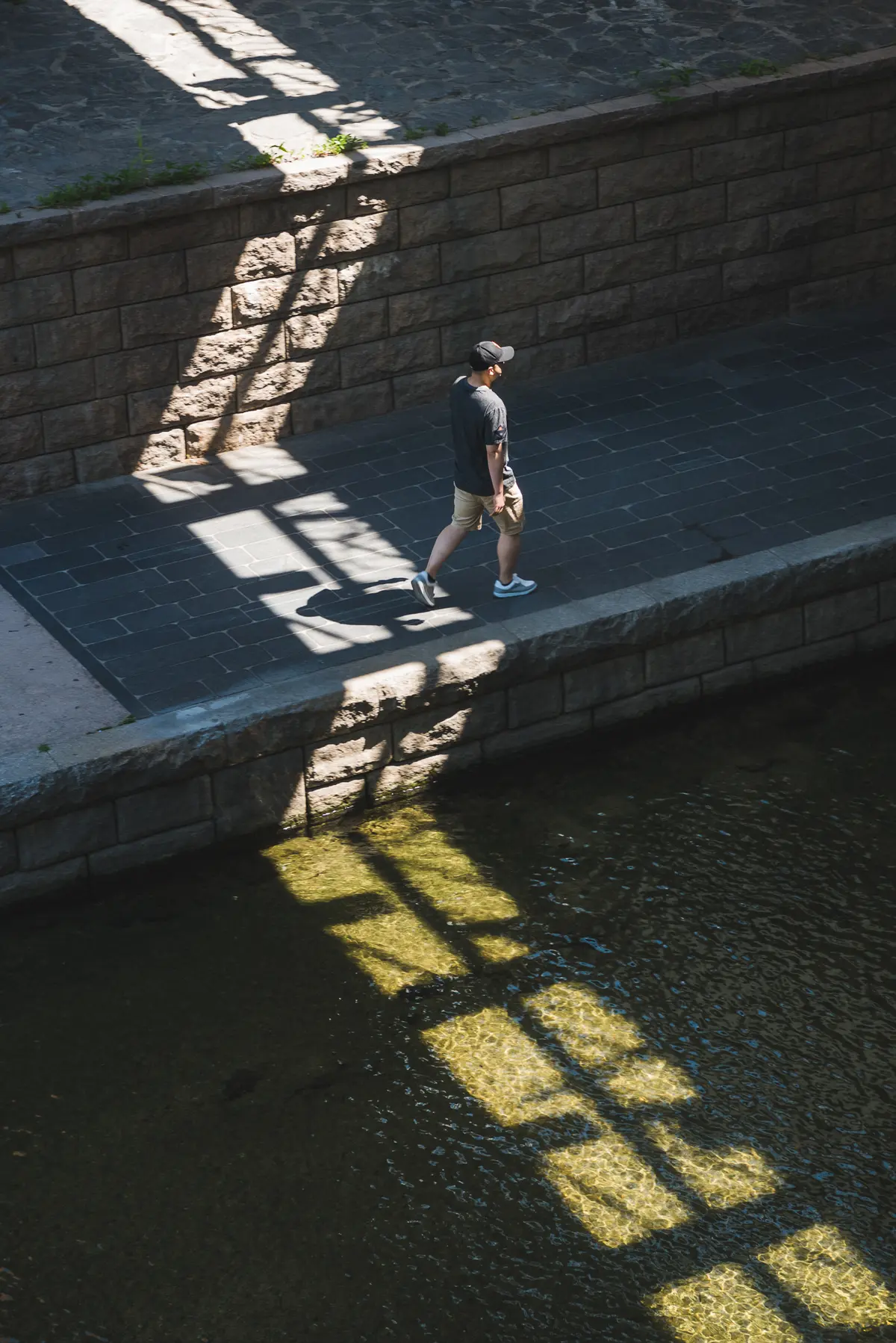 A man walks through a patch of sunlight alongside Cheonggyecheon stream in Seoul