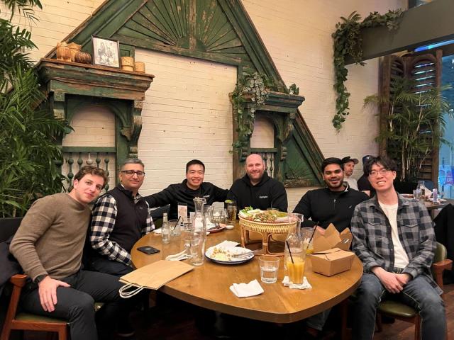The team sharing a meal around a restaurant table