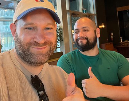 Two Kompas team members smiling and giving a thumbs up