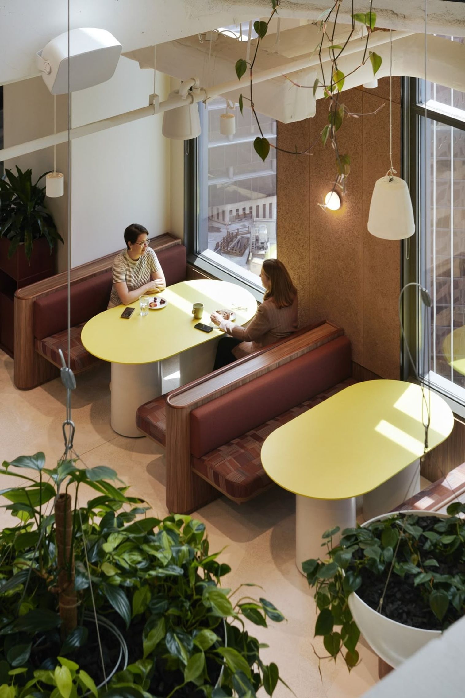 Two colleagues talking over coffee in a bright office booth