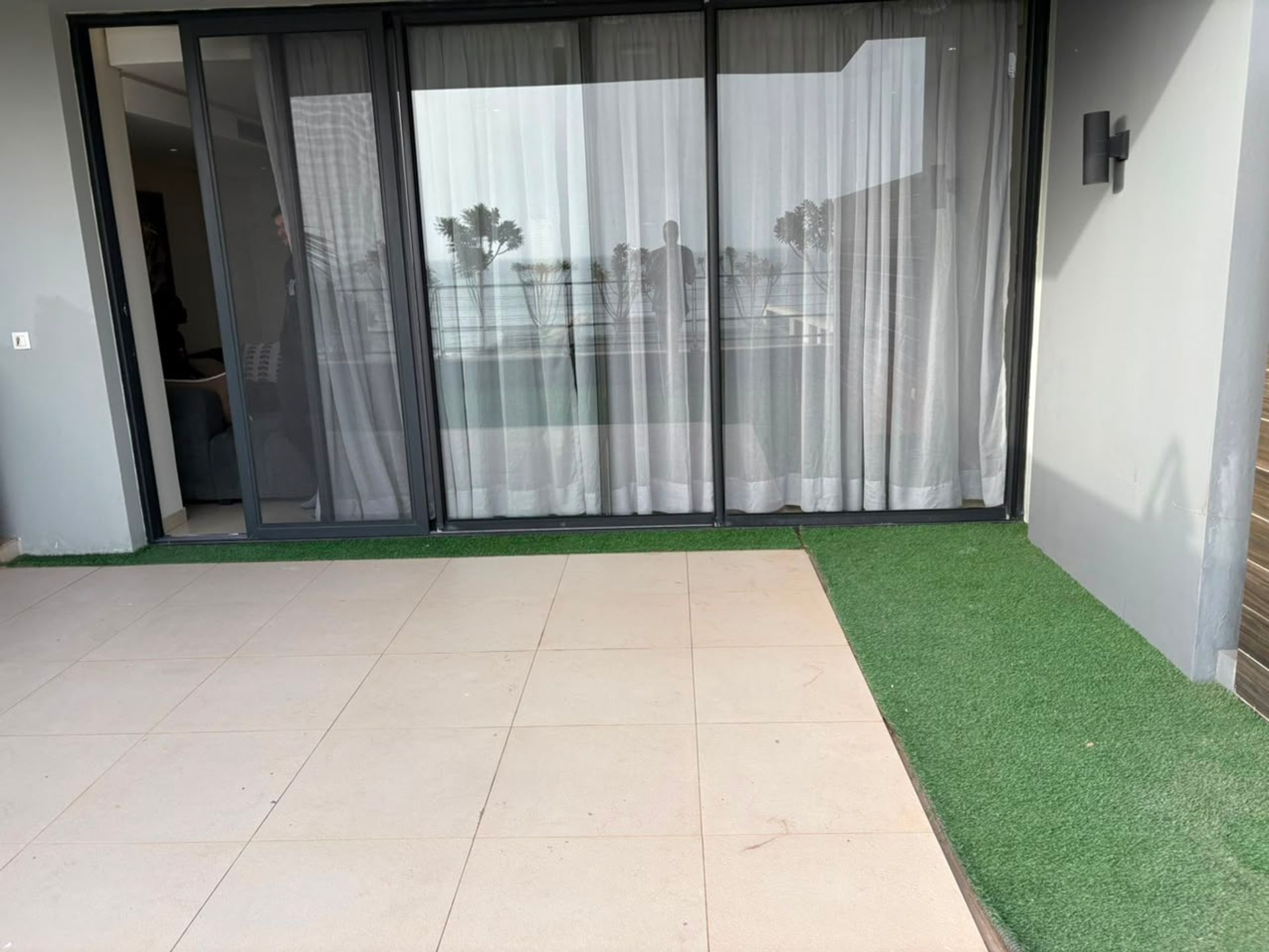 Terrasse carrelée avec gazon synthétique et baies vitrées coulissantes, duplex meublé à Mermoz