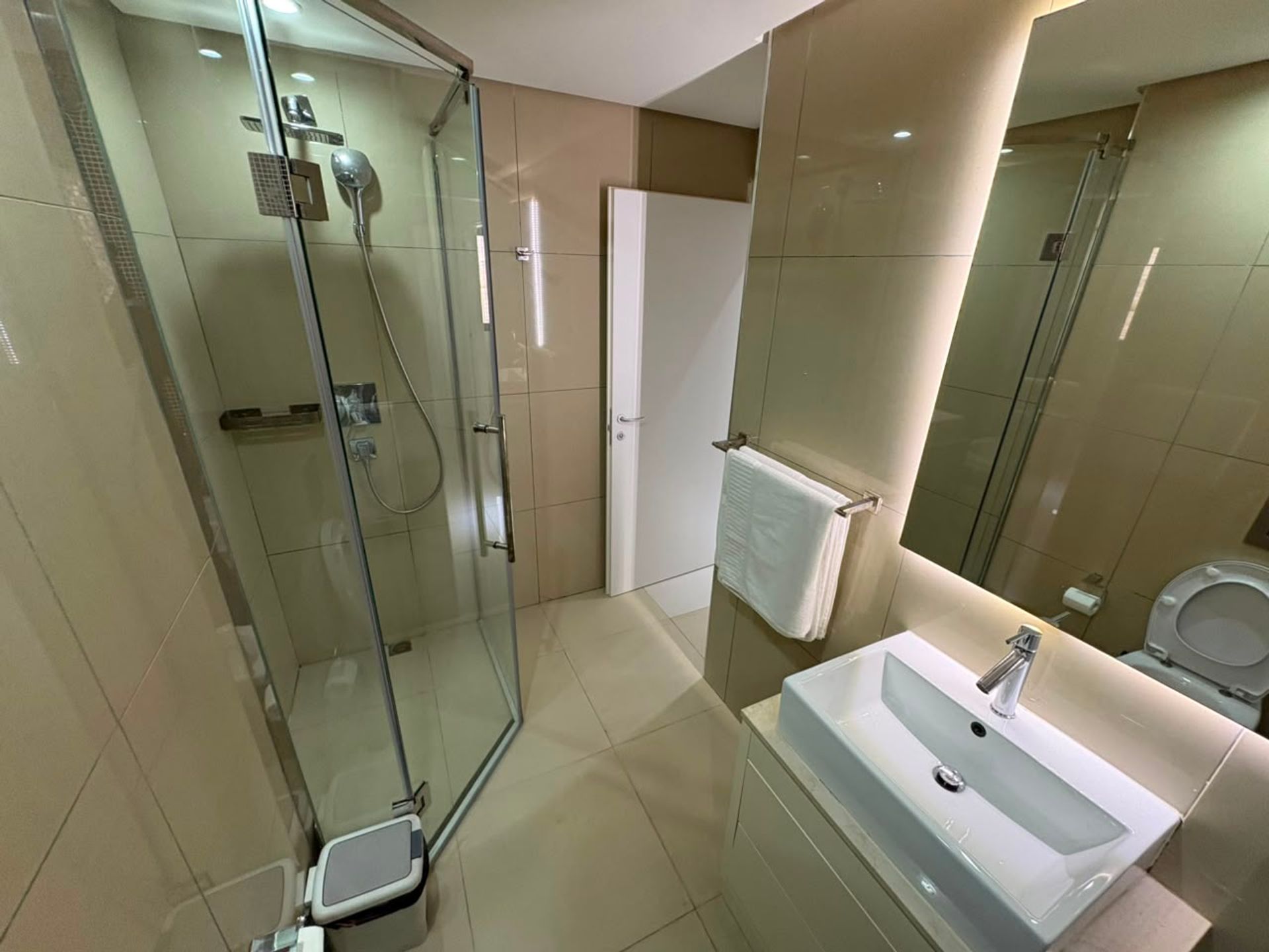 Salle de bain moderne du duplex F3 à Mermoz avec douche vitrée, vasque blanche et miroir rétroéclairé