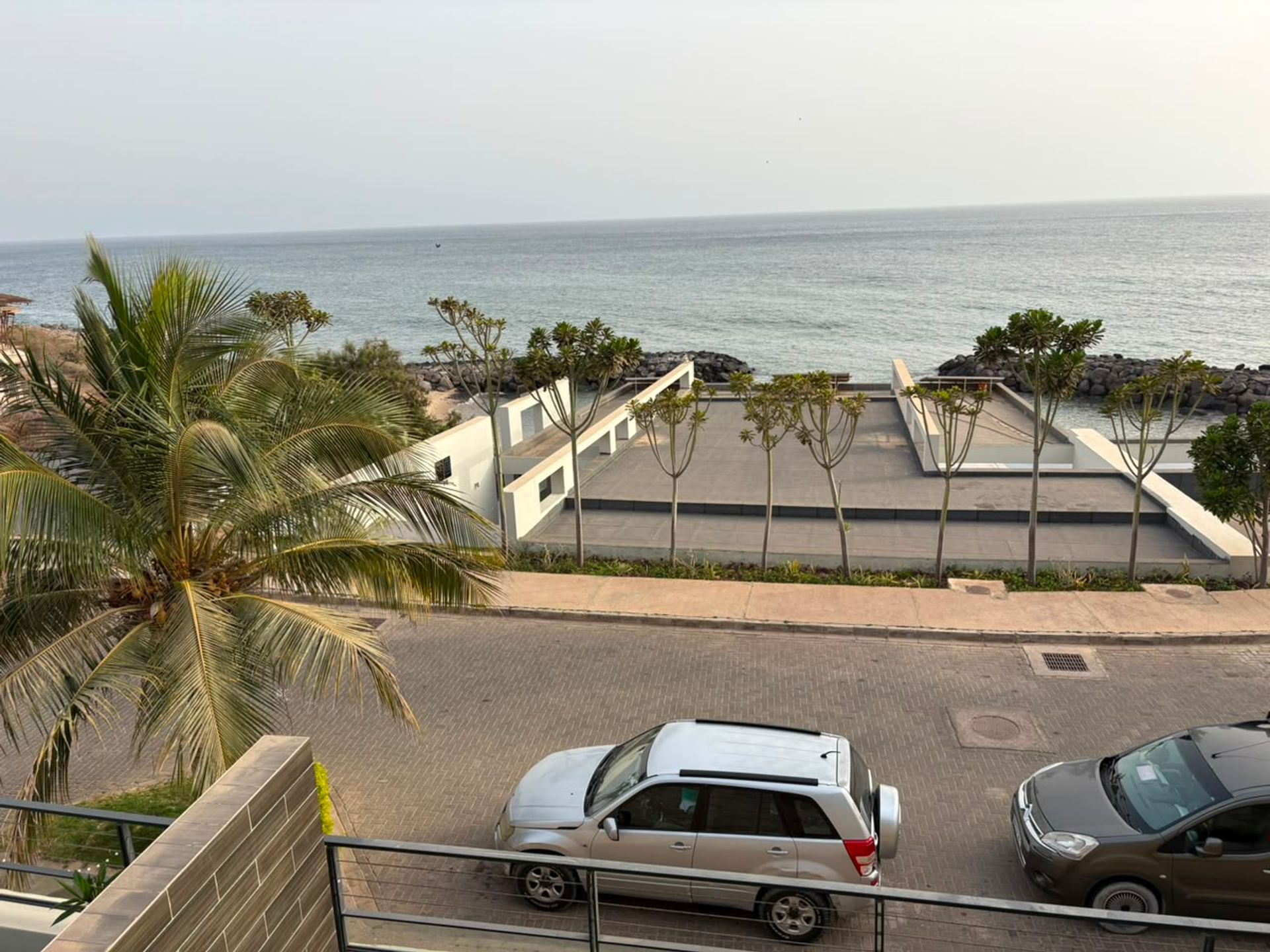 Vue depuis un balcon d'un duplex à Mermoz sur la mer, palmiers et esplanade en bord de plage
