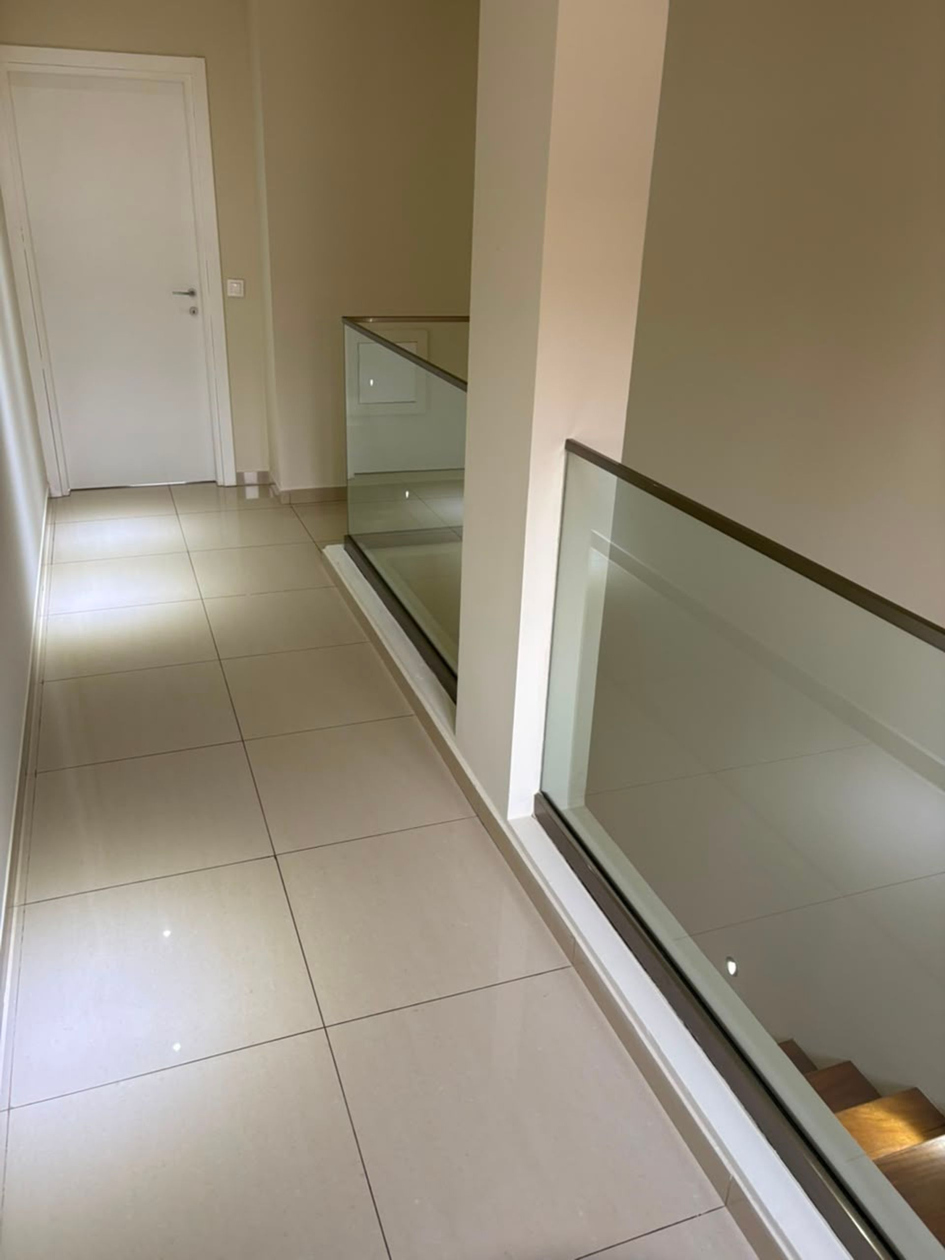 Palier étage avec carrelage beige et garde-corps en verre surplombant l'escalier, duplex F3 à Mermoz