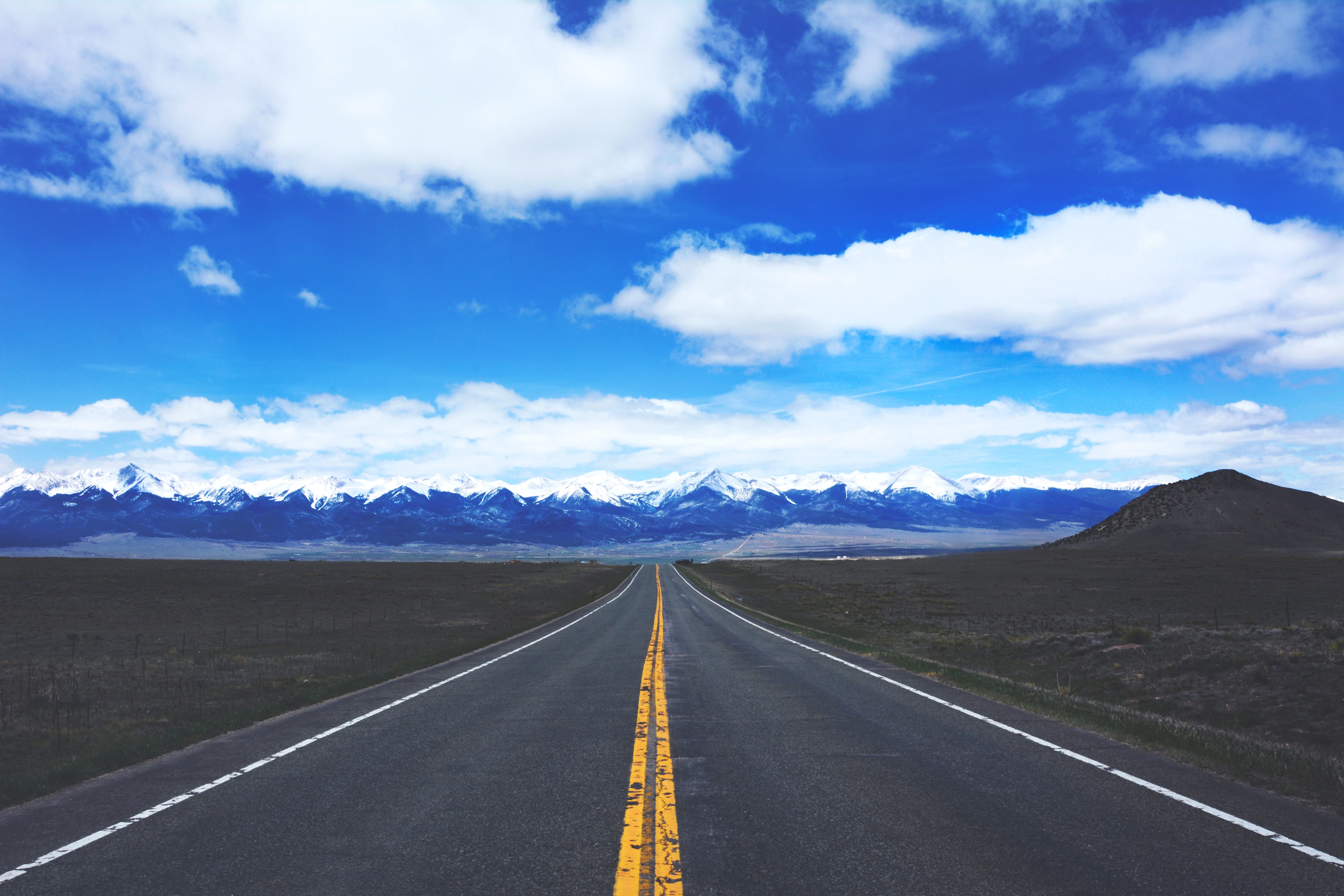 a straight road leading to snow-capped mountains