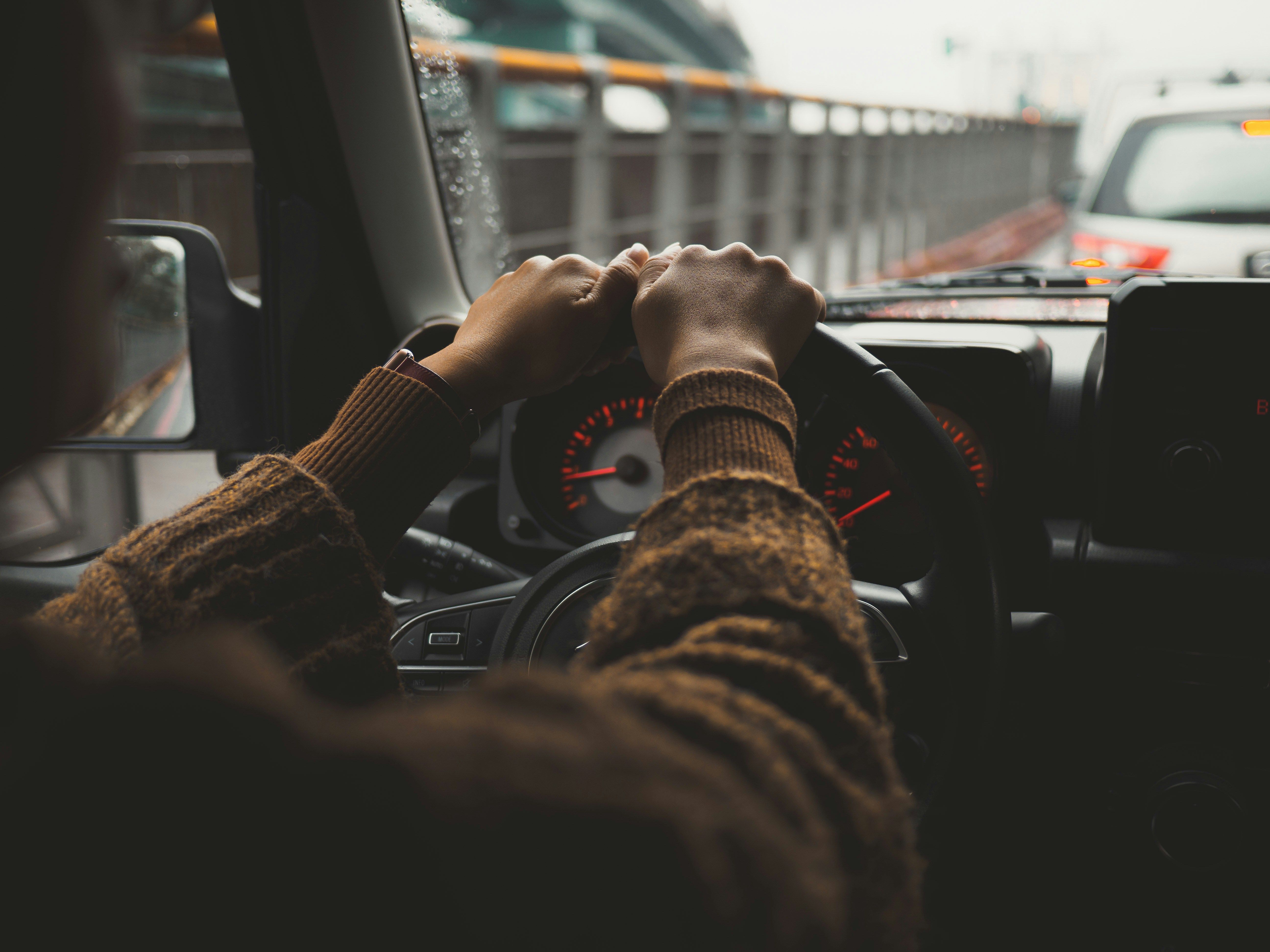 A person driving a car on a city street, photo by Zhong-wei Xu on Unsplash