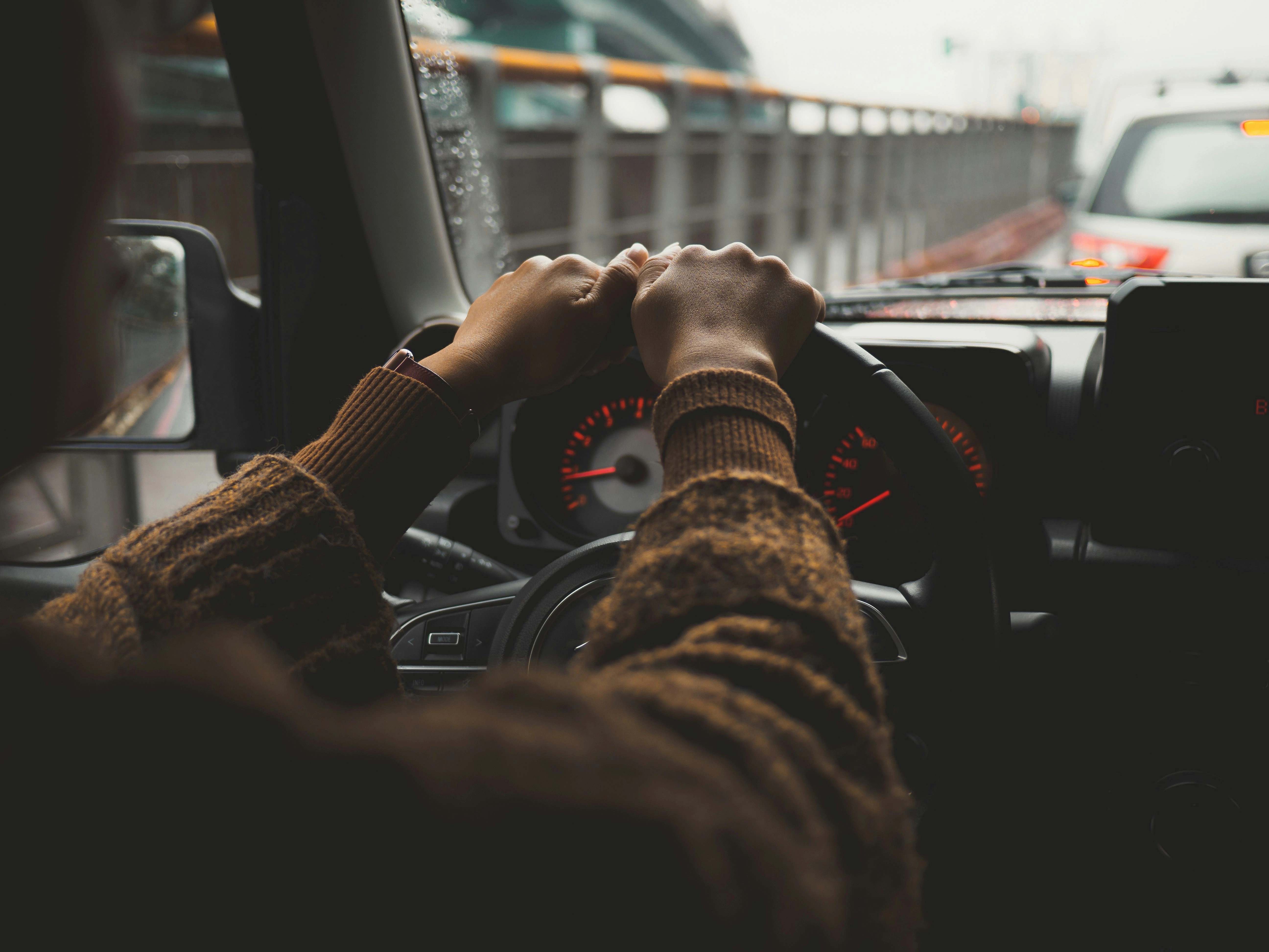 A person driving a car on a city street, photo by Zhong-wei Xu on Unsplash