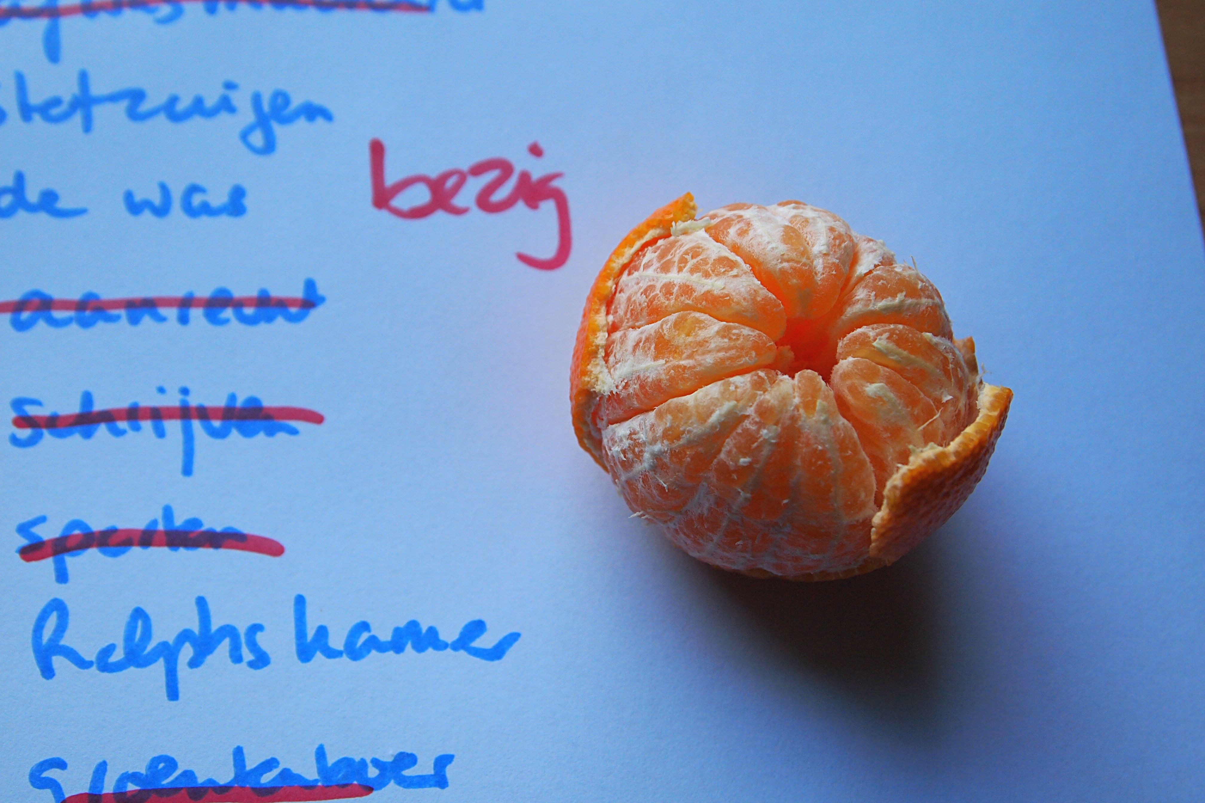 a photo of a half-peeled mandarin next to a half-completed to-do list 