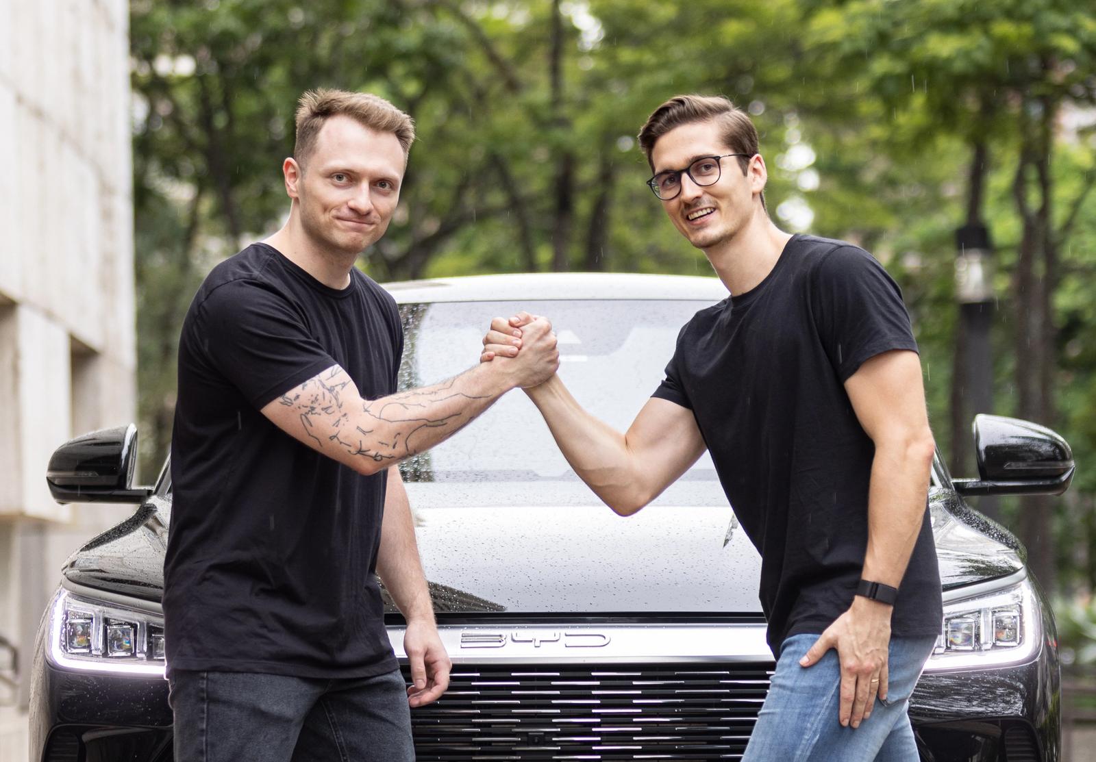 Os fundadores da Rhino, Daniil e Alex, apertando as mãos em frente a um carro blindado preto