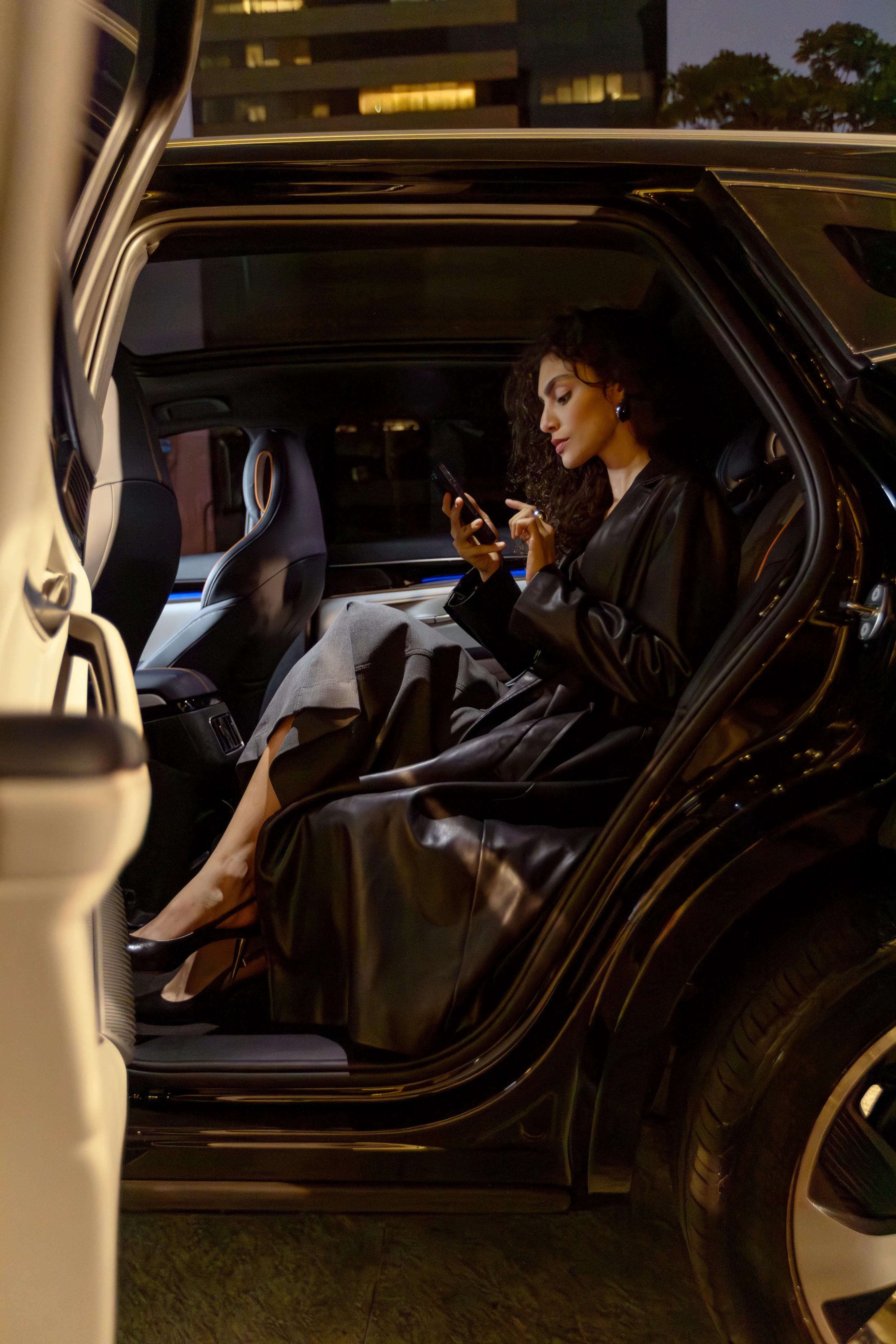 Passageira usando o app Rhino no banco traseiro de um carro blindado à noite