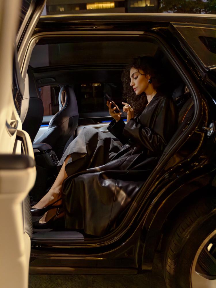 Passageira usando o app Rhino no banco traseiro de um carro blindado à noite