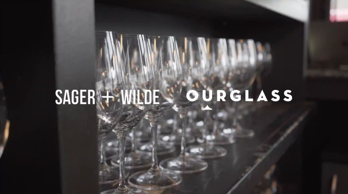 Rows of polished wine glasses at Sager + Wilde, a leading London natural wine bar, with the Ourglass logo overlaid.