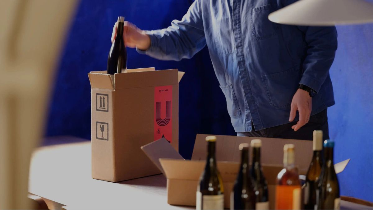 Ourglass founder packing wine subscription boxes with branded packaging and bottles