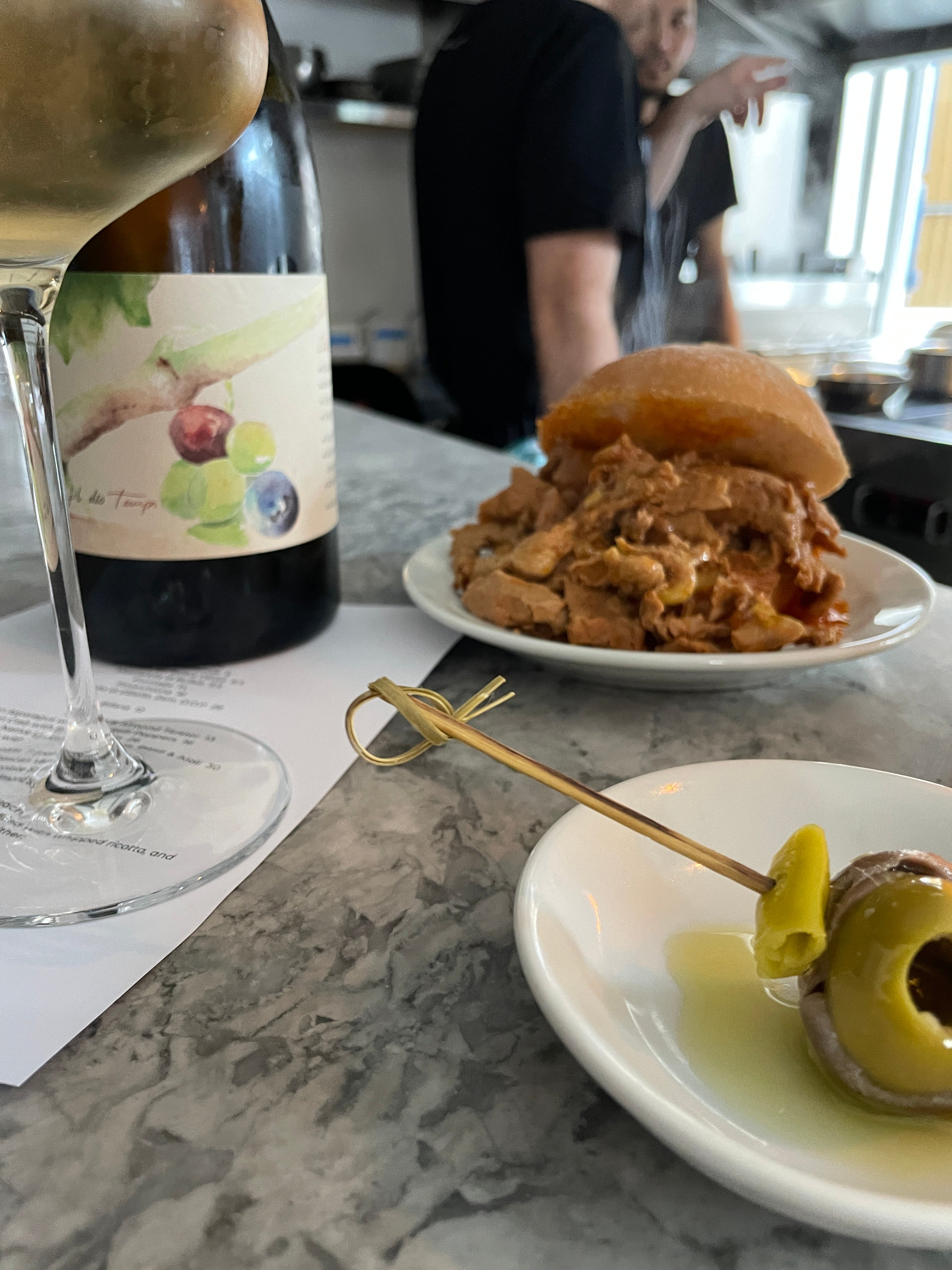 White wine paired with pulled pork bifana sandwich and olive oil on marble bar,