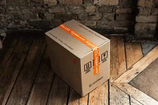 Open wine subscription delivery box containing multiple wine bottles on wooden deck - monthly wine club delivery service