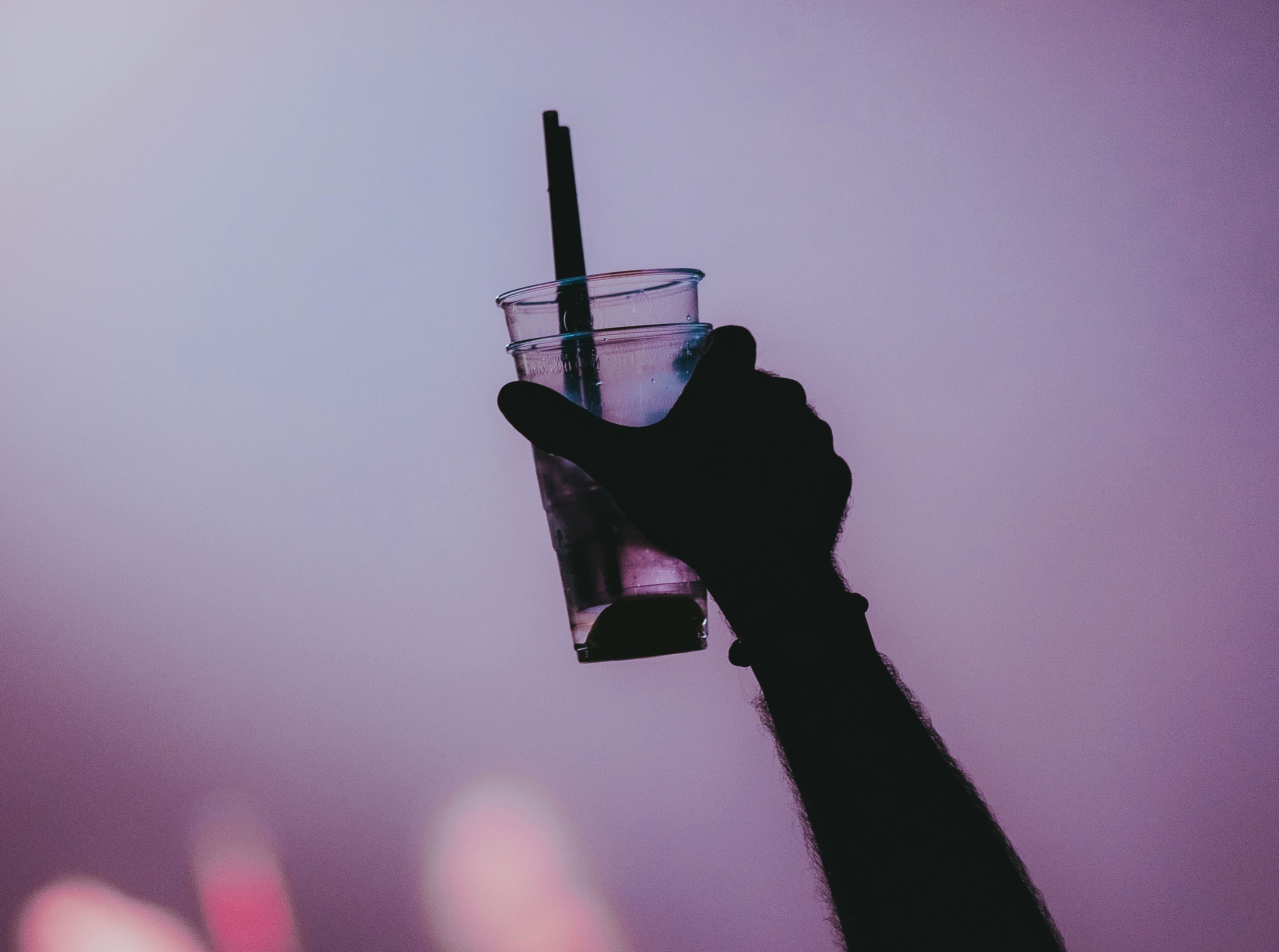 Hand holding plastic cups with plastic straws