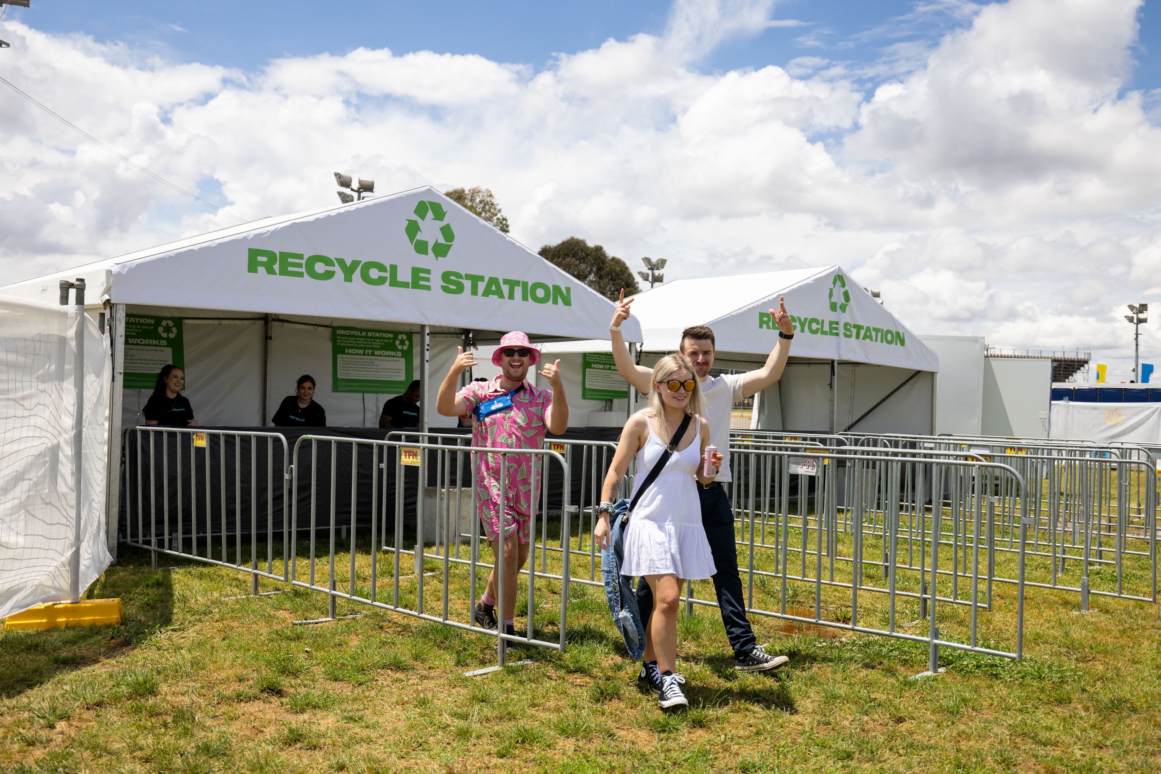 Happy people walking in front of a recycle station at a music festival