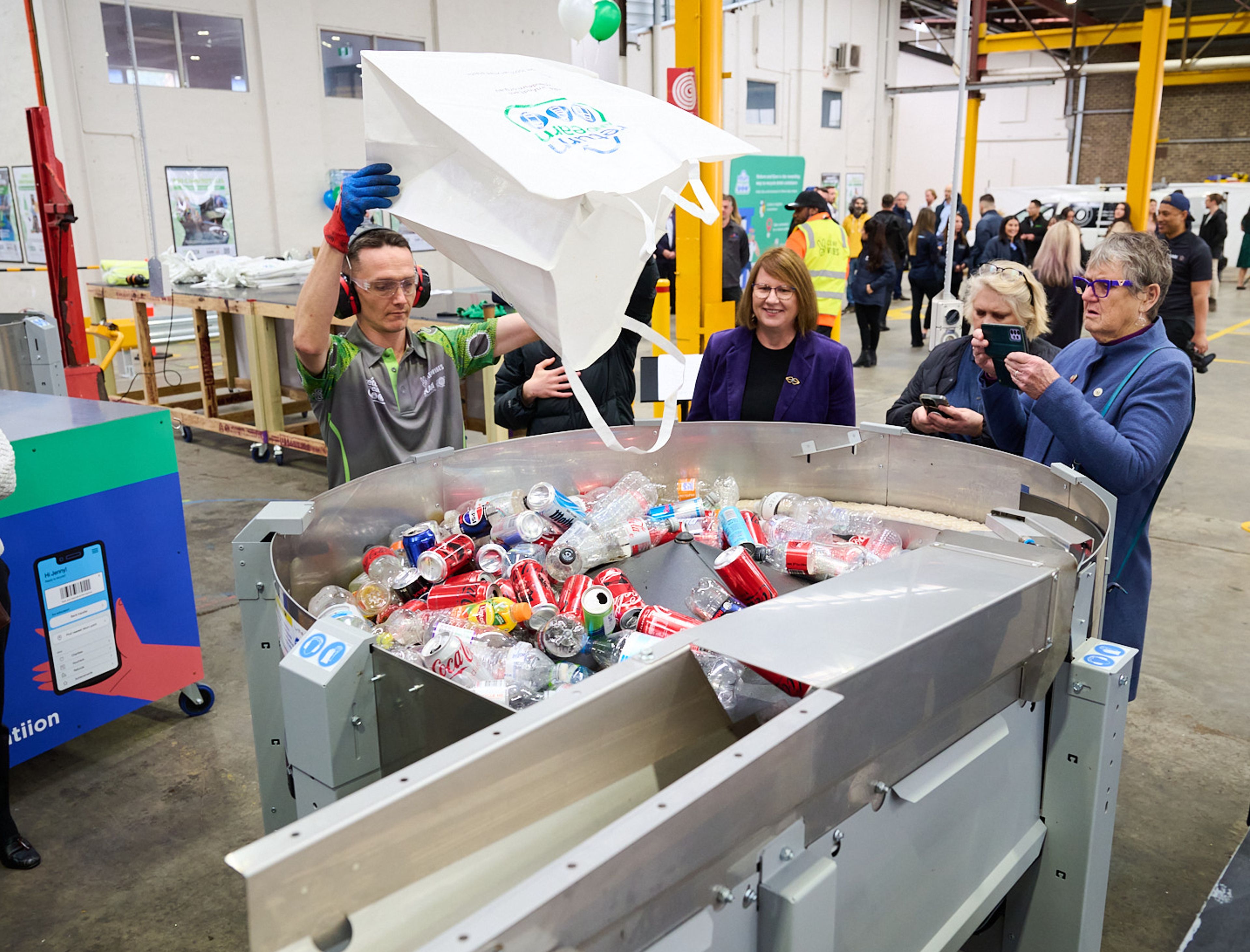 Staff pouring drink containers into singulator machine