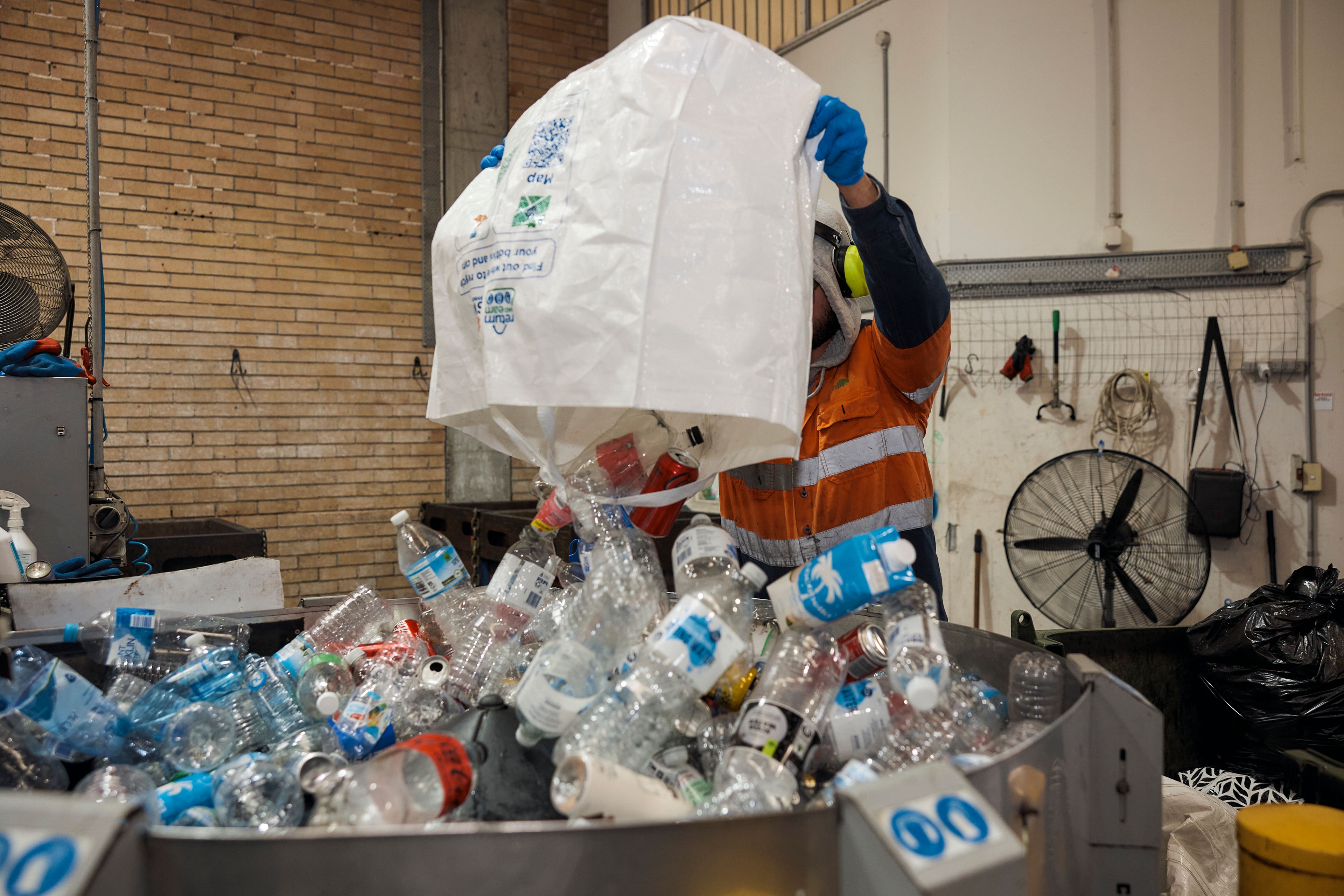 City Return & Earn staff processing empty water bottles at depot