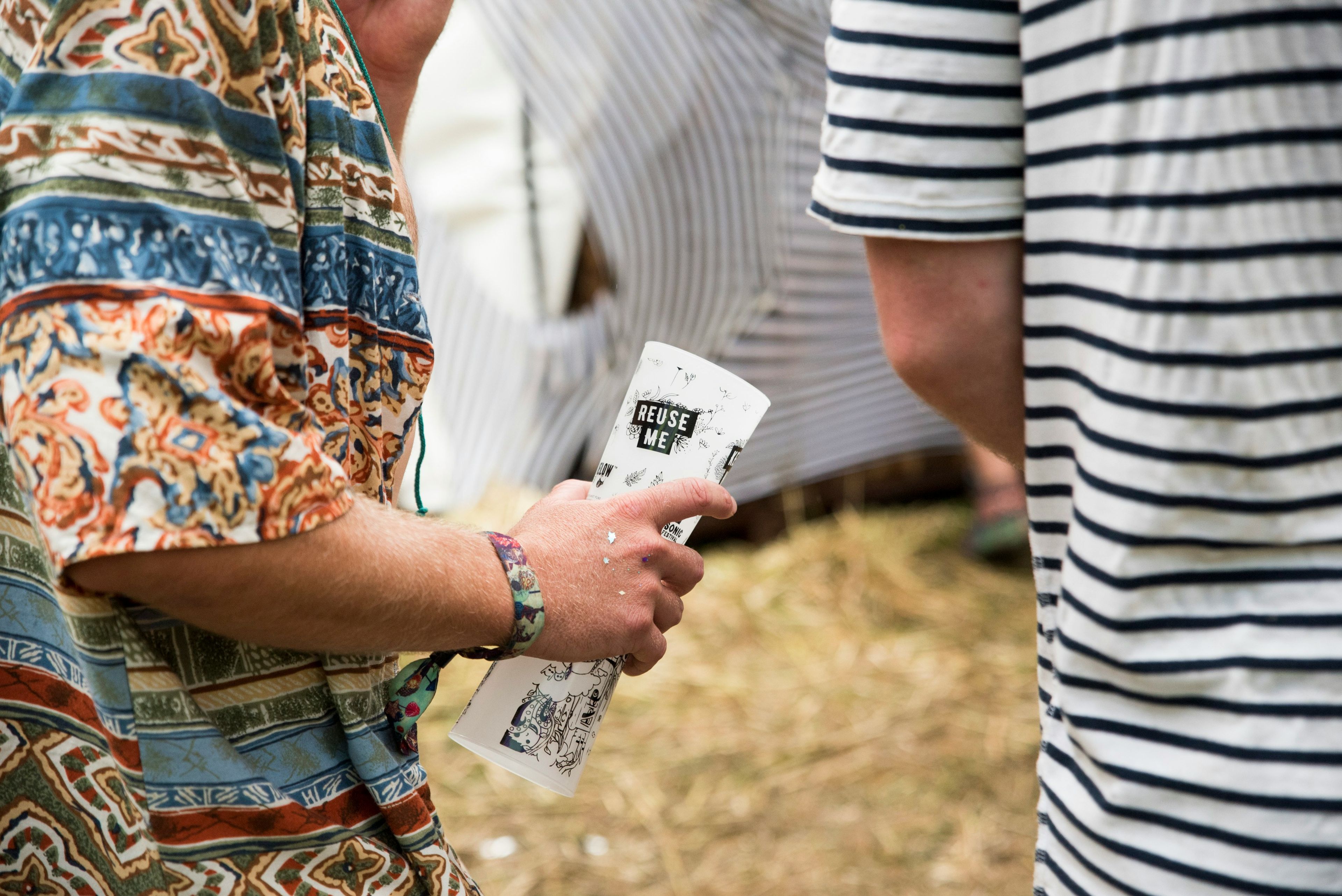 Man walking around with 2 reusable cups at outdoor event