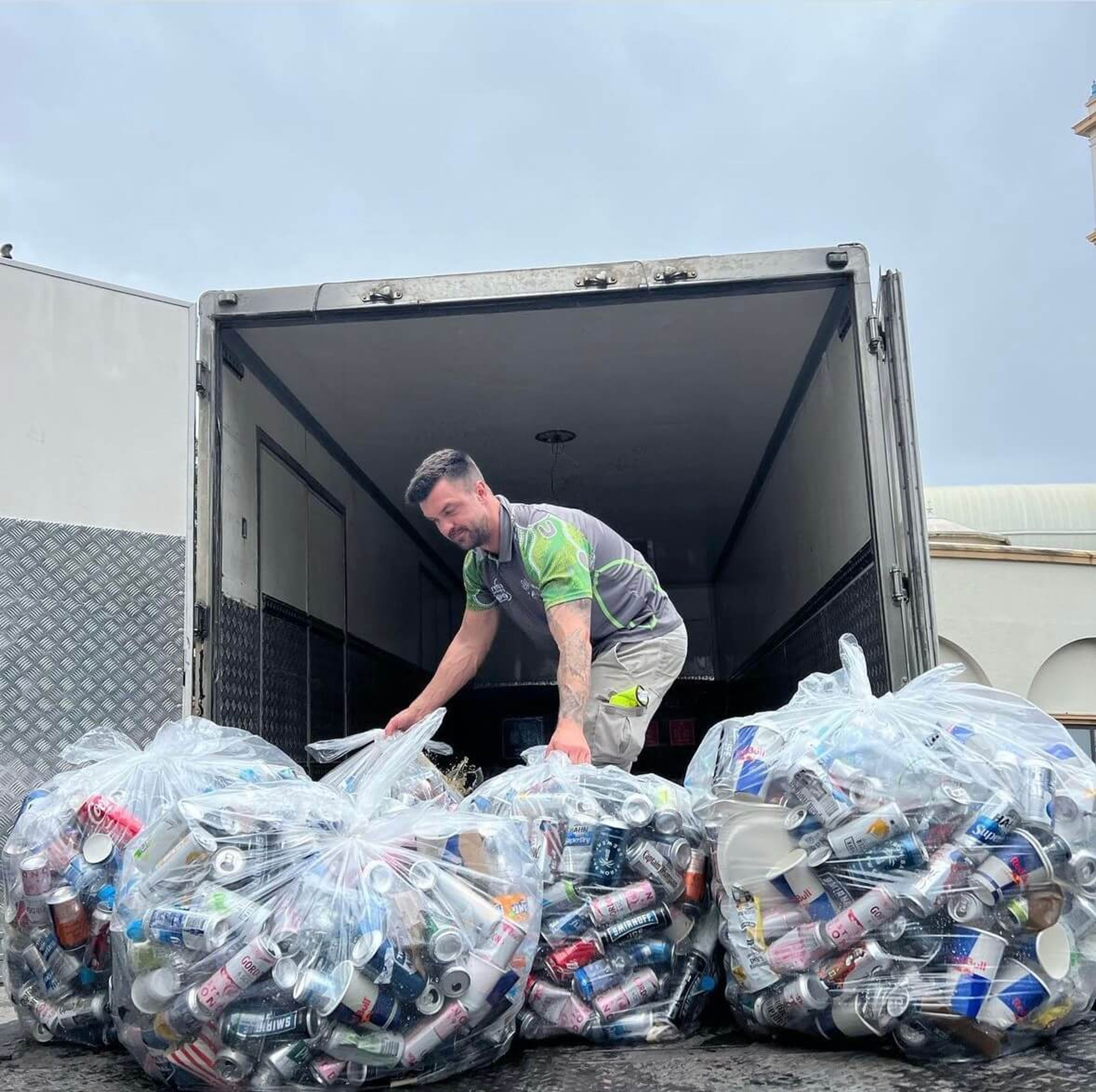 Staff member loading a truck with bags full of cans and plastic bottles for recycling