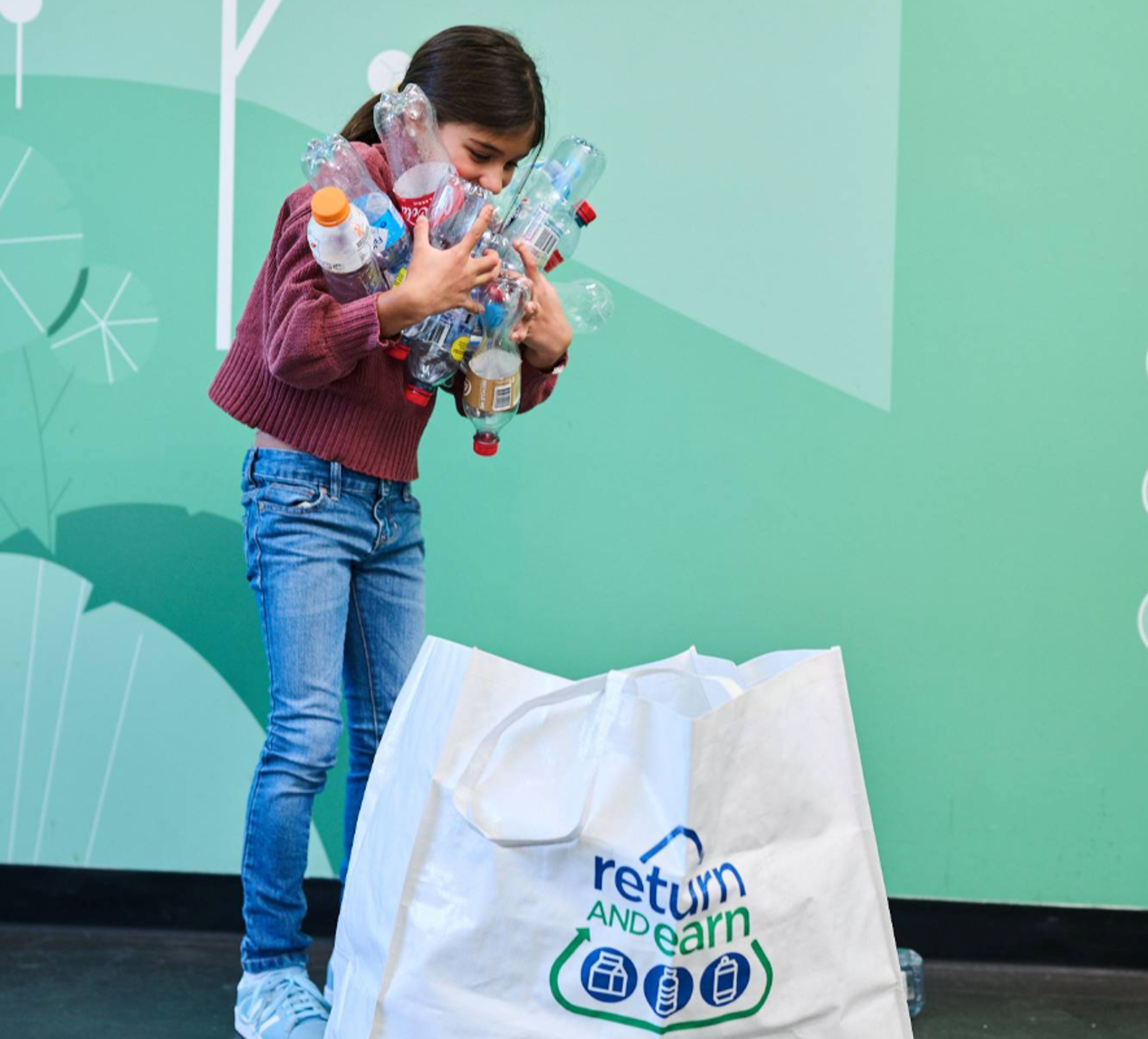 Child holding bottles over Return and Earn Bag
