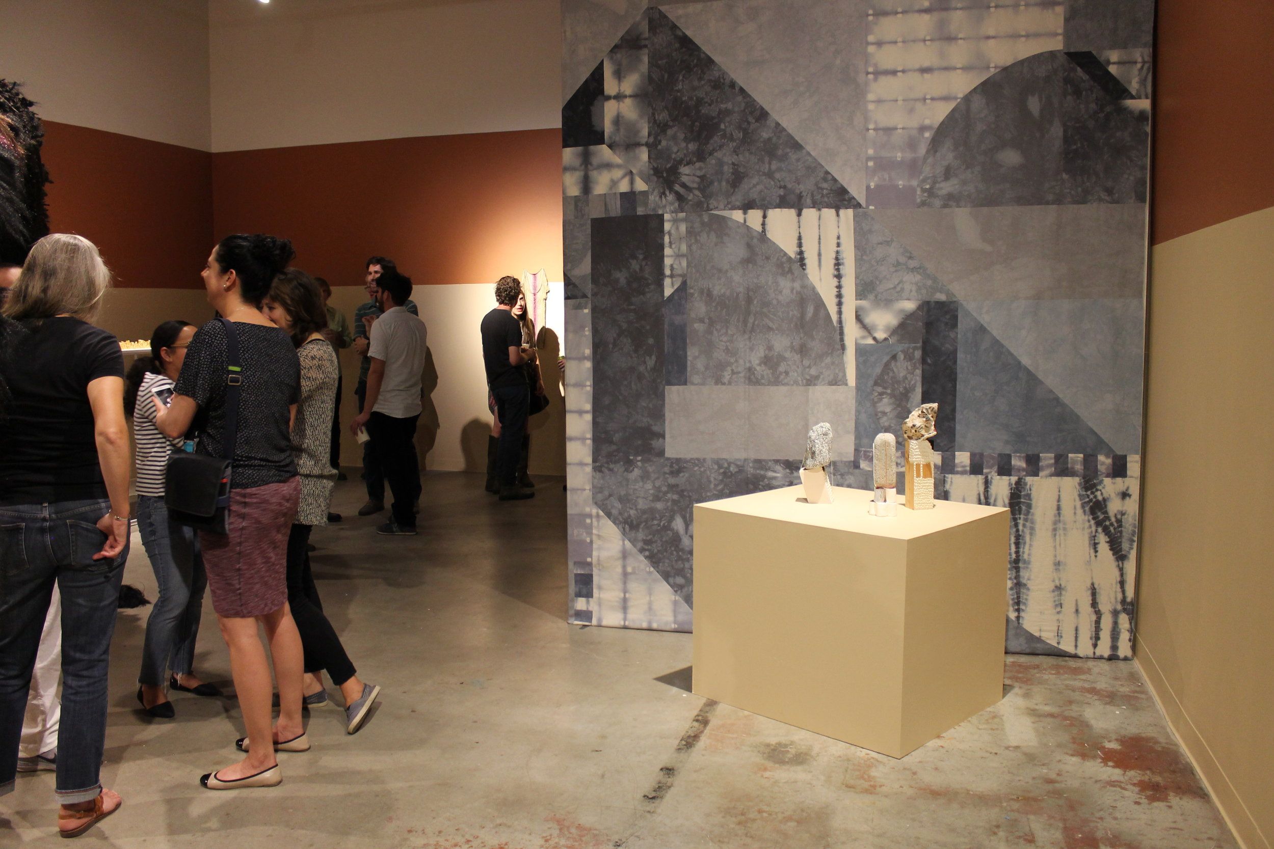 Visitors at an art gallery viewing sculptures on a pedestal