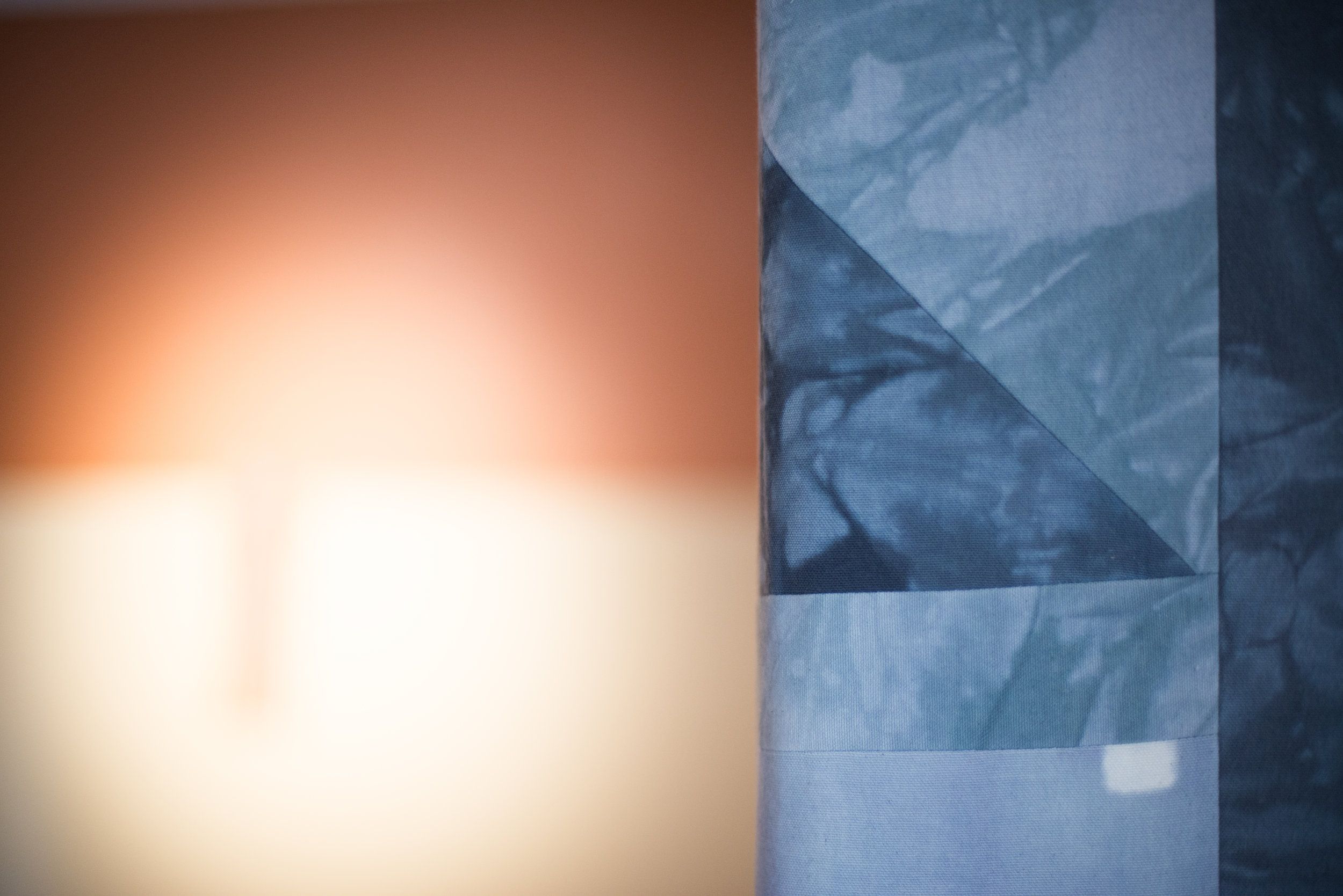 Blue patterned curtain beside blurred light on wall