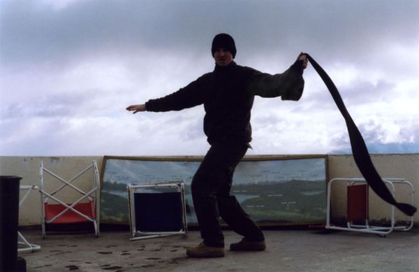 Person balancing on a rooftop terrace with overturned folding chairs