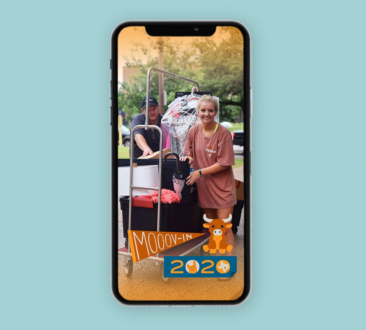 Student pushing a loaded move-in cart, phone screen overlay reading “Mooov-In 2020”