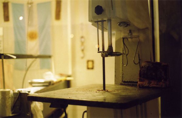 Meat-cutting bandsaw in a butcher shop with Argentine flag behind
