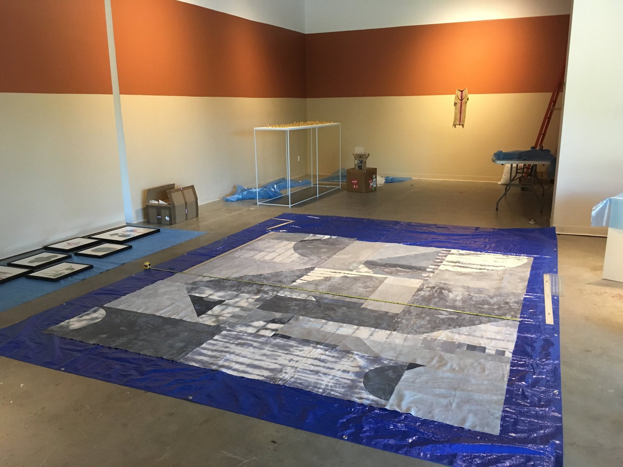 Large abstract mural laid out on floor in gallery workspace