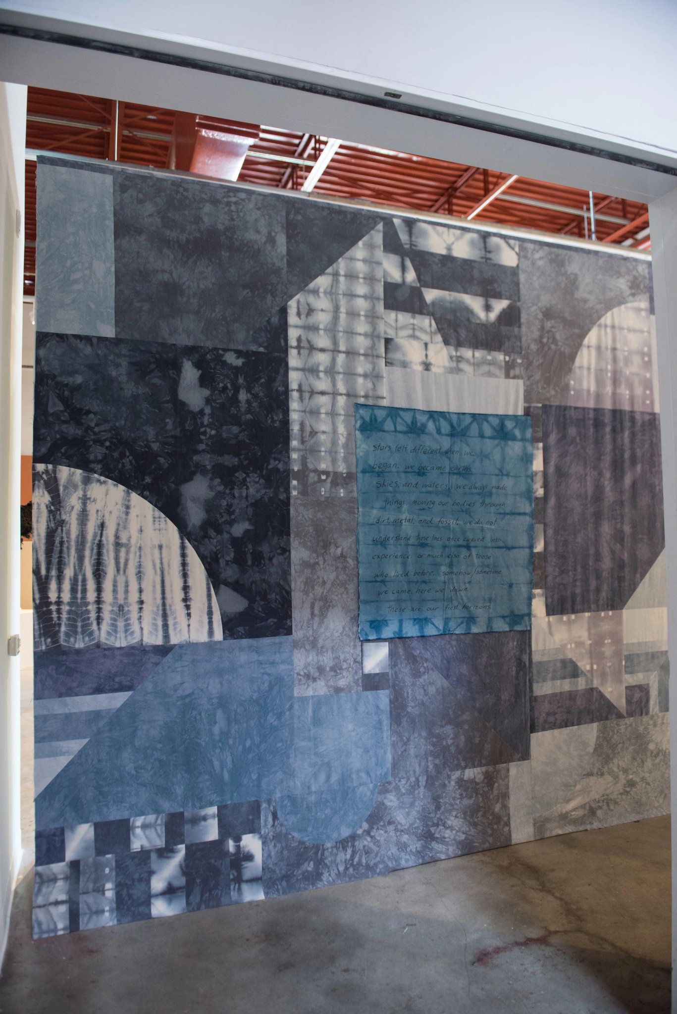 Large abstract wall hanging composed of overlapping geometric, tie-dyed fabric panels