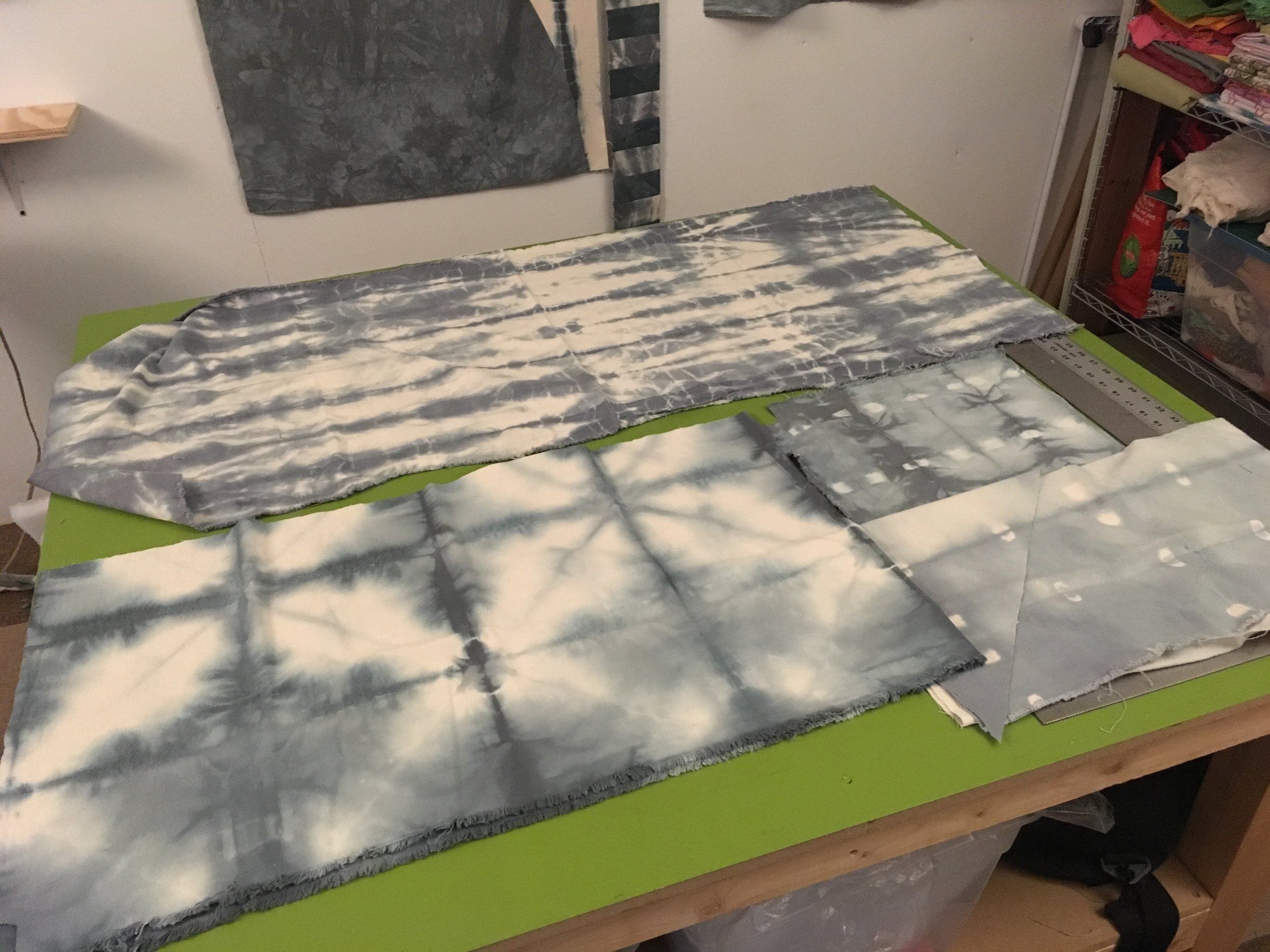 Tie-dyed fabric pieces laid out on a cutting table