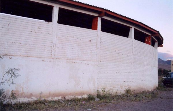 Long white brick wall of an open-sided industrial building outdoors