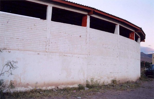 Long white brick wall of an open-sided industrial building outdoors