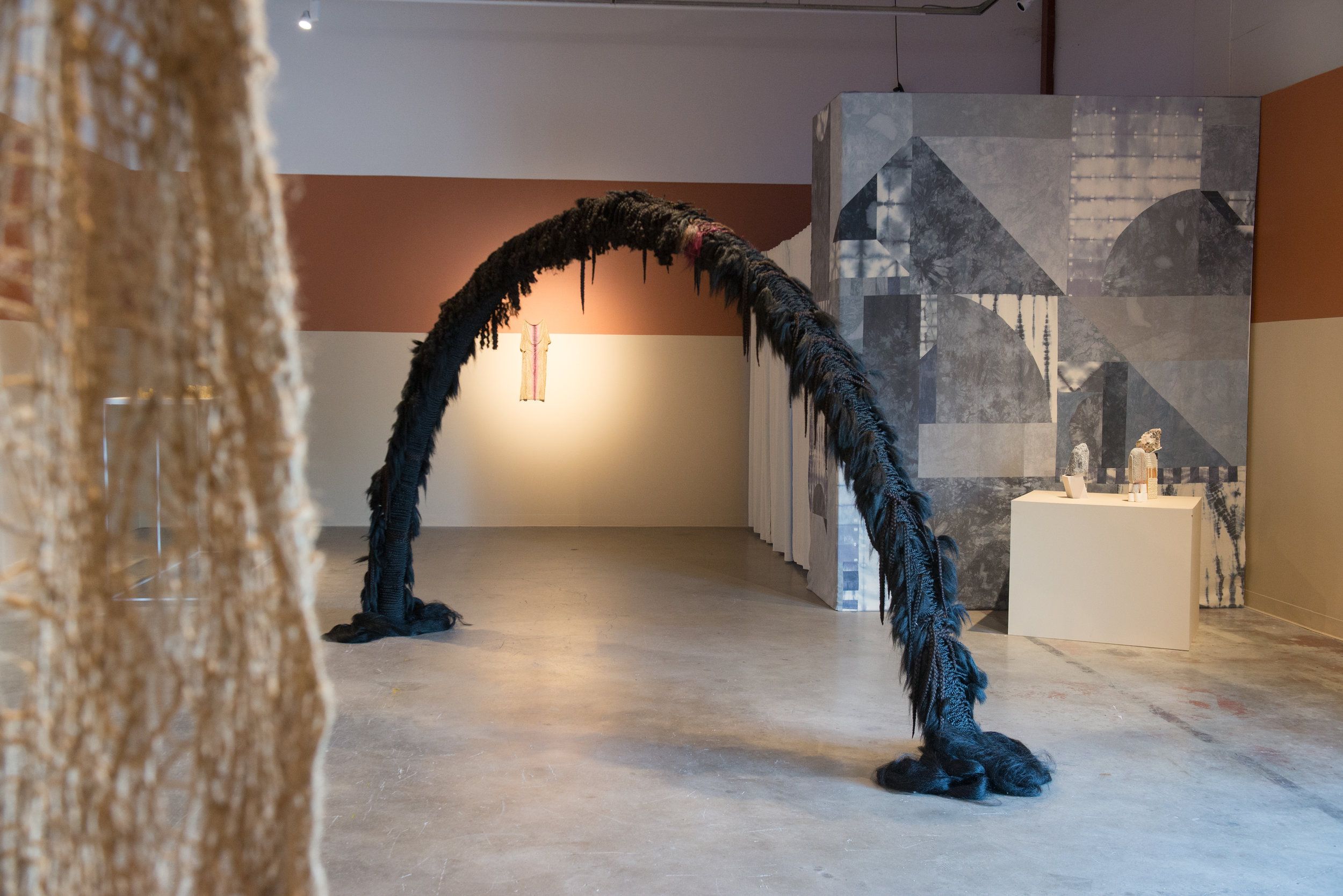 Large black feathered arch sculpture in contemporary gallery installation