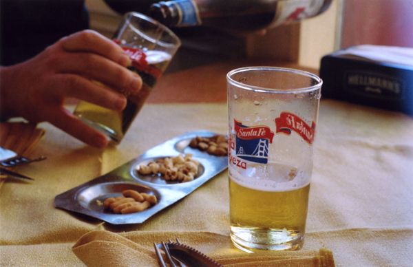 Beer being poured into glasses beside a tray of mixed snacks