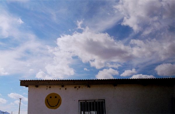 Building wall with painted smiley face beneath a cloudy sky