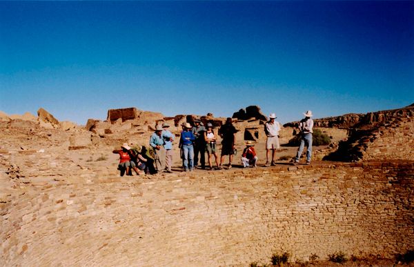 Group of visitors standing on ancient stone ruins in desert landscape