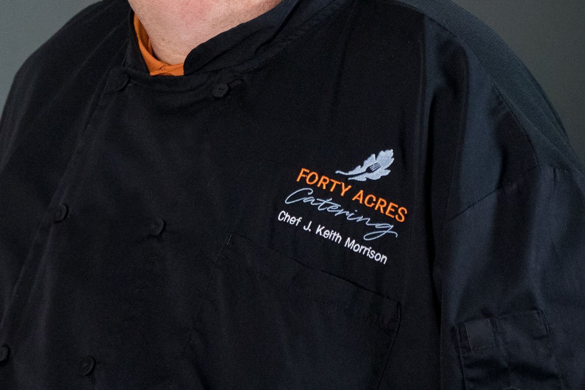 Chef’s black coat embroidered with “Forty Acres Catering, Chef J. Keith Morrison”
