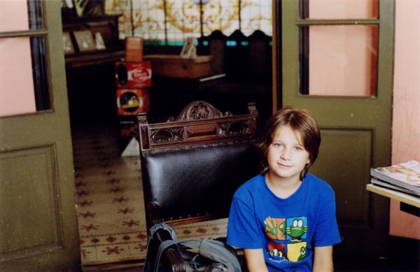 Child in blue cartoon T-shirt sitting on chair in vintage room