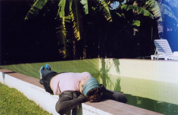 Person lying face down on pool edge beside empty swimming pool