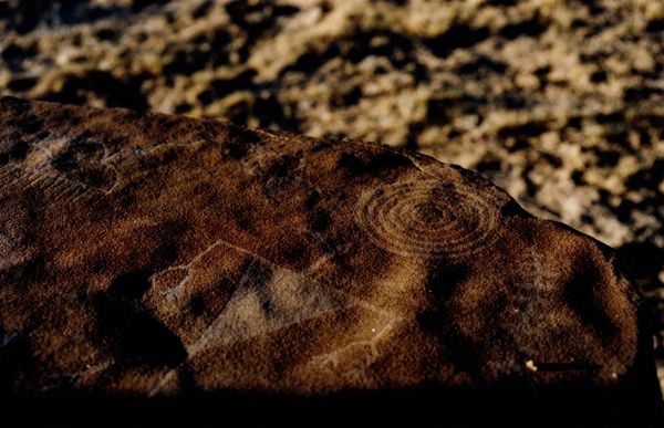 Rock surface with faint spiral and geometric petroglyph carvings