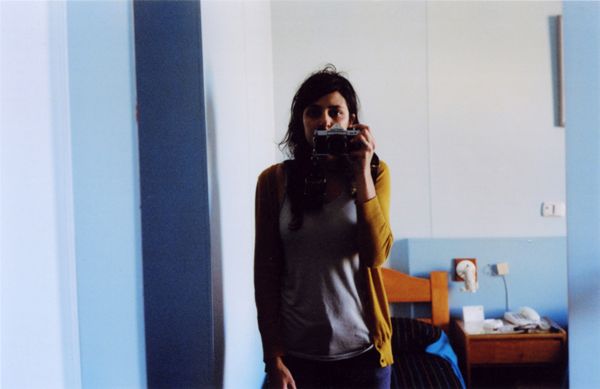 Person taking a mirror selfie in a simple bedroom