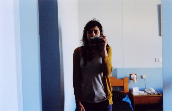 Person taking a mirror selfie in a simple bedroom