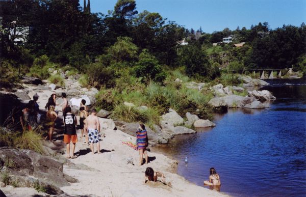 People relaxing and swimming on a rocky riverbank in summer